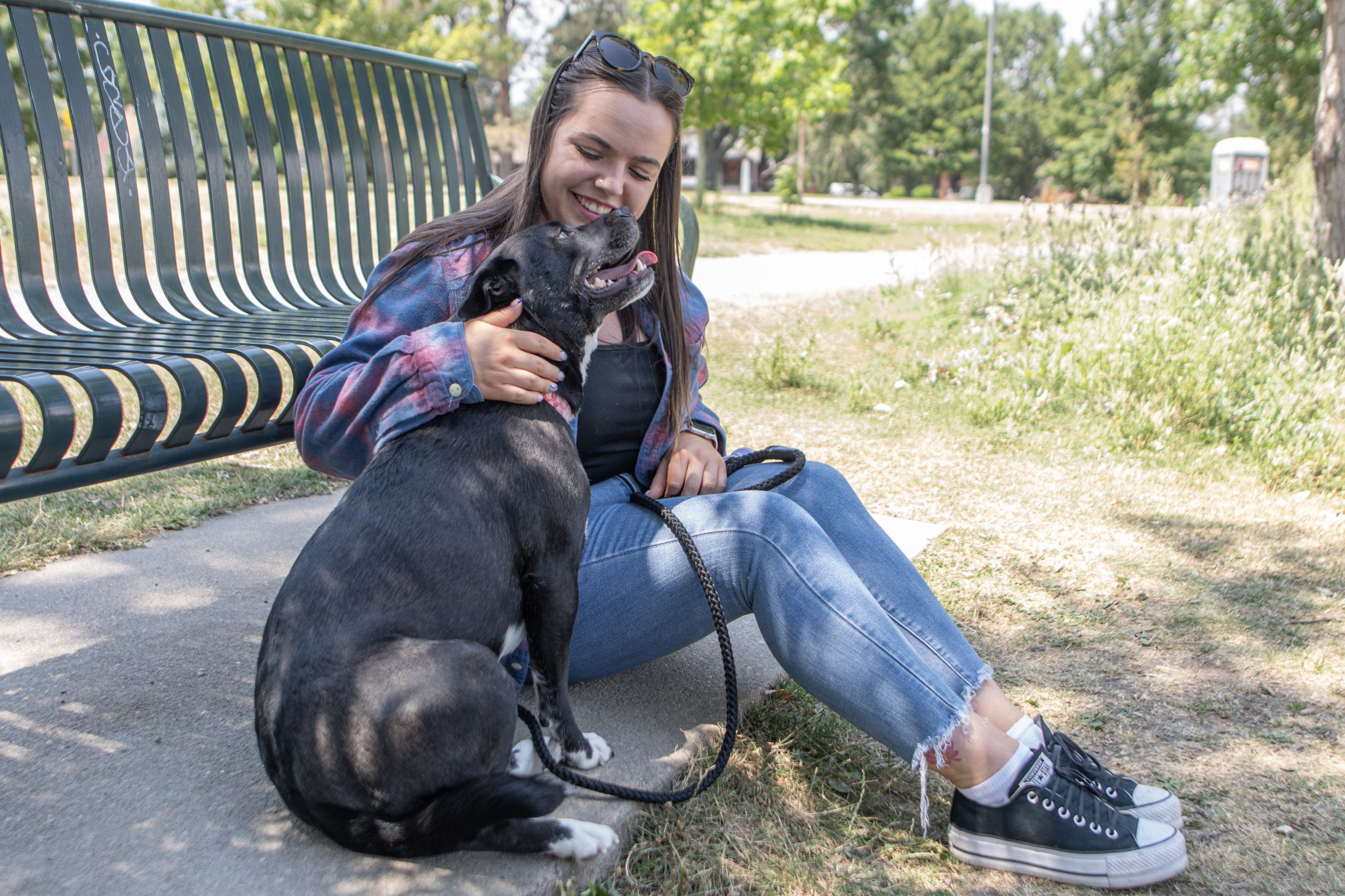 Woman sitting with dog by bench.